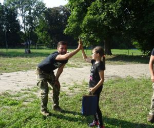 Uczestnik spotkania odbiera nagrodę, która wręcza Wójt Gminy Hrubieszów, radny oraz prowadzący survival.