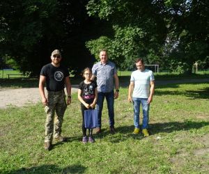 Uczestnik spotkania odbiera nagrodę, która wręcza Wójt Gminy Hrubieszów, radny oraz prowadzący survival.