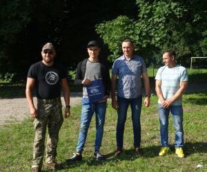 Uczestnik spotkania odbiera nagrodę, która wręcza Wójt Gminy Hrubieszów, radny oraz prowadzący survival.