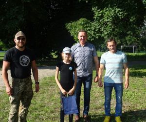 Uczestnik spotkania odbiera nagrodę, która wręcza Wójt Gminy Hrubieszów, radny oraz prowadzący survival.