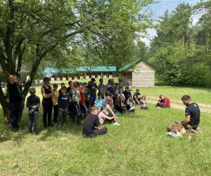 Grupa dzieci siedzi w kręgu, obok prowadzący zajęcia.