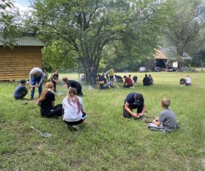 Grupa dzieci uczy się rozpalania ognia.