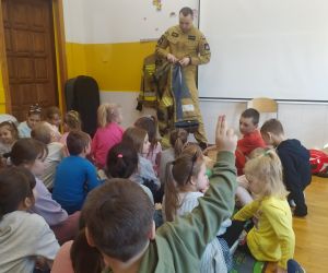 Strażak prezentuje umundurowanie.