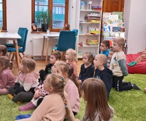 Dzieci słuchają bajki czytanej przez bibliotekarkę.