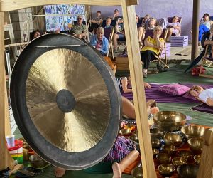 Zdjęcie przedstawia publiczność na koncercie, który odbywa się w stodole, a na pierwszym planie gong.