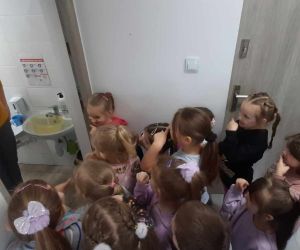 Przedszkolaki z pedagogiem szkolnym podczas przeprowadzania doświadczenia z wodą.