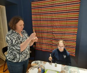 Prowadząca pokazuje technikę malowania woskiem pszczelim