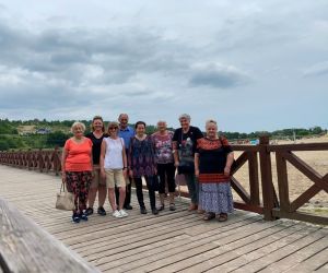 Zdjęcie przedstawia grupę ludzi na świeżym powietrzu stojących na molo.