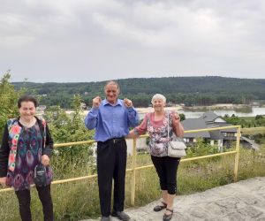 Zdjęcie przedstawia 3 osoby dorosłe na świeżym powietrzu, w tle panorama miasta.