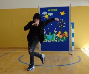 Uczeń tańczy na tle dekoracji wiosennej