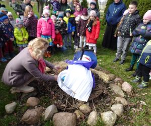 Opiekun Samorządu Uczniowskiego podpala Marzannę na ognisku, wokoło stoją uczniowie i nauczyciele