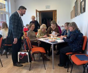 Prowadzący spotkanie przy grupie kobiet siedzących przy stoliku