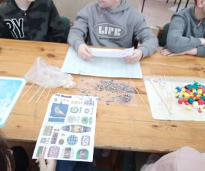 Uczniowie zapoznają się z kartami zawierającymi wzory na paciorki