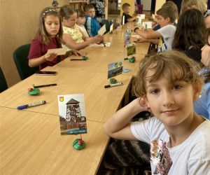 Zdjęcie przedstawia grupę dzieci wewnątrz budynku, dzieci wykonują stojak/podstawkę w kształcie biedronki, na zdjęcie.