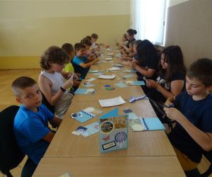 Zdjęcie przedstawia grupę dzieci wewnątrz budynku. Dzieci wykonują 