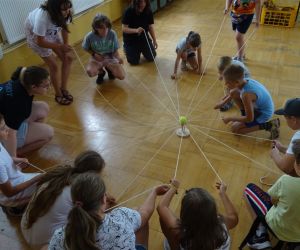 Zdjęcie przedstawia grupę dzieci wewnątrz budynku. Dzieci bawią się w zabawę - Koło komunikacji. 