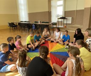 Zdjęcie przedstawia dzieci wewnątrz budynku bawiące się chusta animacyjną.