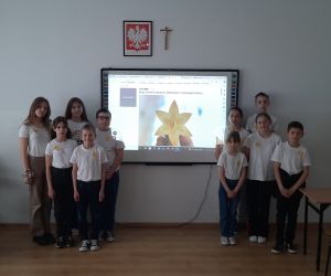 Uczniowie stoją przy tablicy na tle logo akcji