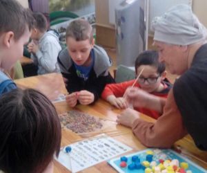 Uczniowie klasy trzeciej wykonują paciorki pod opieką prowadzącej w stroju gockim