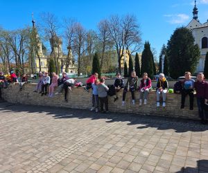 Dzieci siedzą na murku przed Domem Kultury