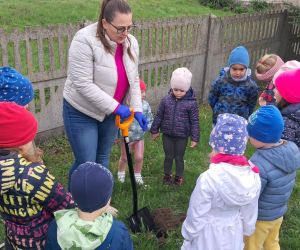 Dzieci sadzą klon przy przedszkolu.