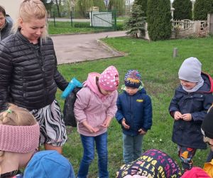 Dzieci zbierają śmieci wokół przedszkola.