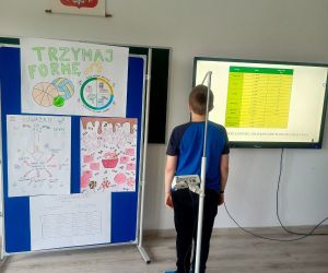 Uczeń stoi na wadze z wysuniętą miarką wzrostu