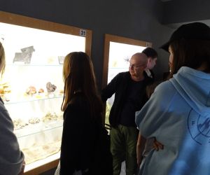 Uczniowie z przewodnikiem przy gablocie z minerałami w Muzeum 