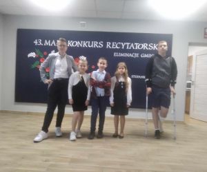 Dwie uczennice i trzech uczniów naszej szkoły na scenie na tle tablicy dekoracyjnej