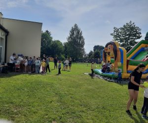 Uczniowie przy stoisku z watą cukrową i popcornem, w tle zjeżdżalnie