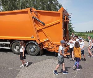 Uczniowie oglądają śmieciarkę z zewnątrz