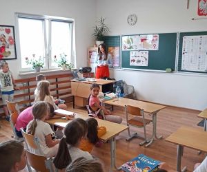 Uczniowie siedzą przy stolikach i słuchają prelekcji o segregacji odpadów