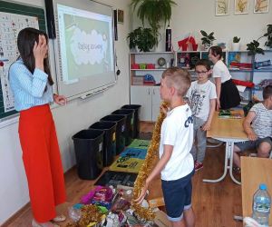 Dwóch uczniów segreguje odpady pod nadzorem prowadzącej zajęcia