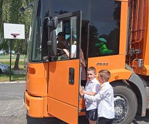 Dwóch uczniów wchodzi do szoferki śmieciarki