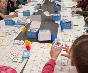 Uczniowie przy stole podczas programowania robota