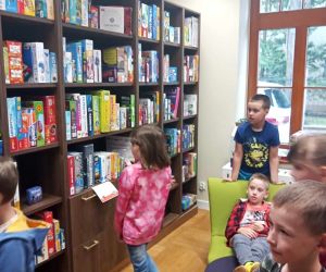 Uczniowie przy regałach z książkami