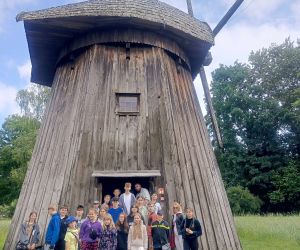 Uczniowie z opiekunem stoją przed dawnym młynem