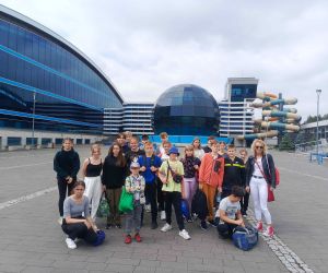 Uczniowie z opiekunem stoją przed parkiem wodnym