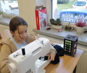 Uczennica zszywa materiał na maszynie