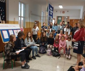 Uczniowie i nauczyciele wsłuchują się w czytany utwór