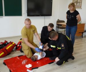 Strażacy zakładają opatrunek uciskowy uczniowi