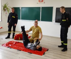 Strażak prezentuje ułożenie ciała dziecka przy omdleniu