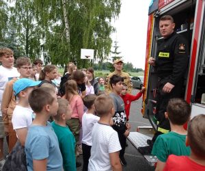 Uczniowie słuchają strażaka i oglądają sprzęty znajdujące się w wozie strażackim