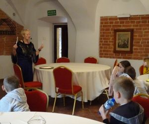 Uczniowie słuchają wykładu przewodniczki o właściwym zachowaniu przy stole