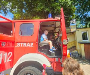 Chłopcy siedzą za kierownicą wozu strażackiego