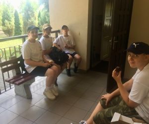 Kilkoro uczniów siedzi na ławce i spożywa przygotowany poczęstunek