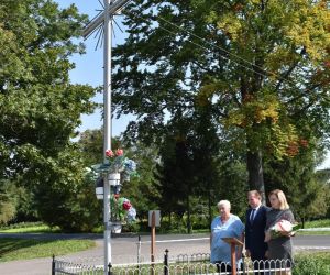 Osoby stoją na dworze pod krzyżem.