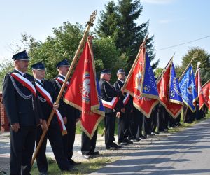 Straż OSP w mundurach stoi na świeżym powietrzu.