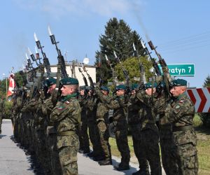 Żołnierze stoją w szeregu i oddają strzał z broni.