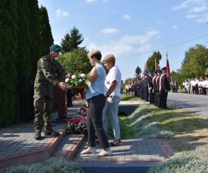 Osoby składają kwiaty przy pomniku. 